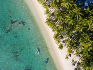 foto van bovenaf met strand, blauw water en palmbomen