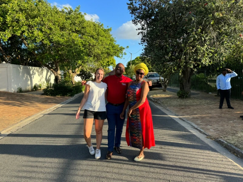 Vrouw staat met twee lokale bewoners op een straat in Zuid-AFrika