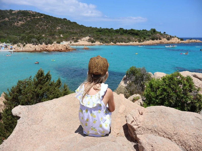 Kind op een rots die uitkijkt over costa Smeralda