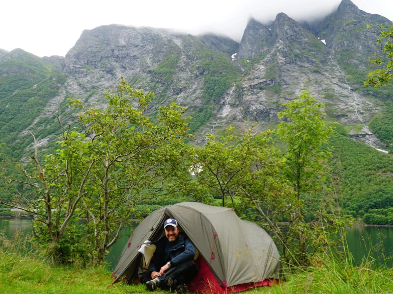 Vader zit in zijn tent aan de rand van een meer.
