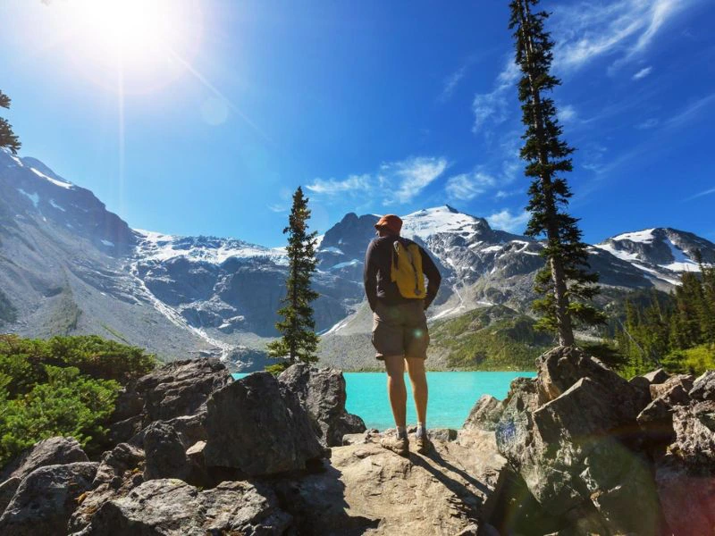 Hiker staat naar een knalblauw bergmeer tussen de bergen.