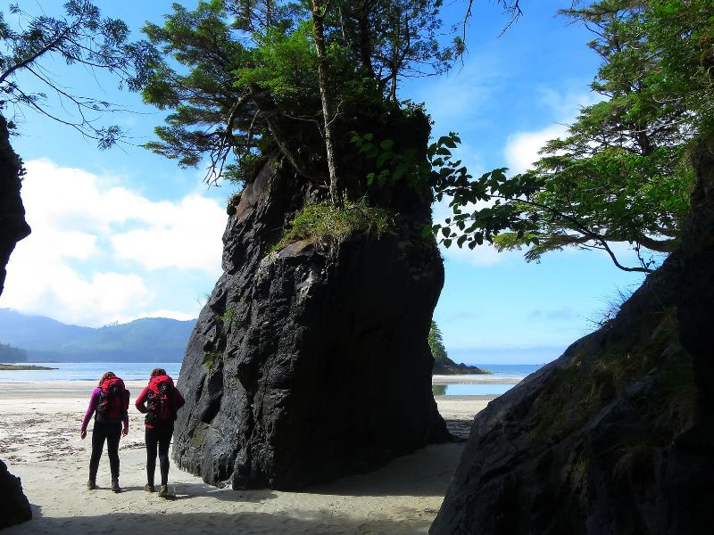 Reizigers lopen tussen de rotsen door een strand op.