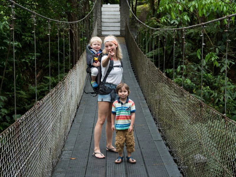 Vrouw met haar twee kinderen op een loopbrug in Costa Rica