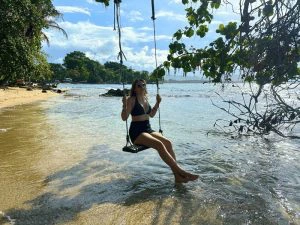 Jonge vrouw op een schommel op het strand, Costa Rica