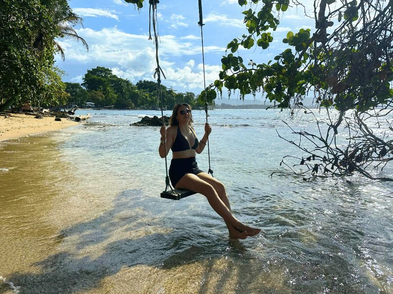 Jonge vrouw op een schommel op het strand, Costa Rica