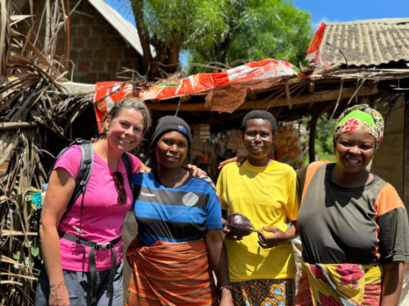 Vrouw op de foto met lokale bewoners voor houten huisjes met kleurrijke kleding