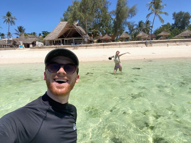 Selfie in het helder blauwe water van zanzibar met wit zand en palmbomen op de achtergrond