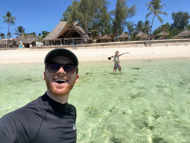 Selfie in het helder blauwe water van zanzibar met wit zand en palmbomen op de achtergrond