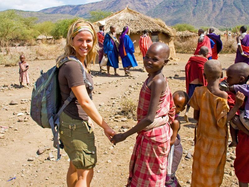 Reiziger staat hand in hand met een vrouw van de Masai.