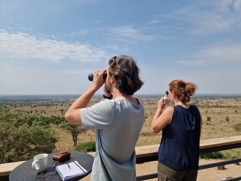 Reizigers genieten van het uitzicht over het Serengeti van hun terras.