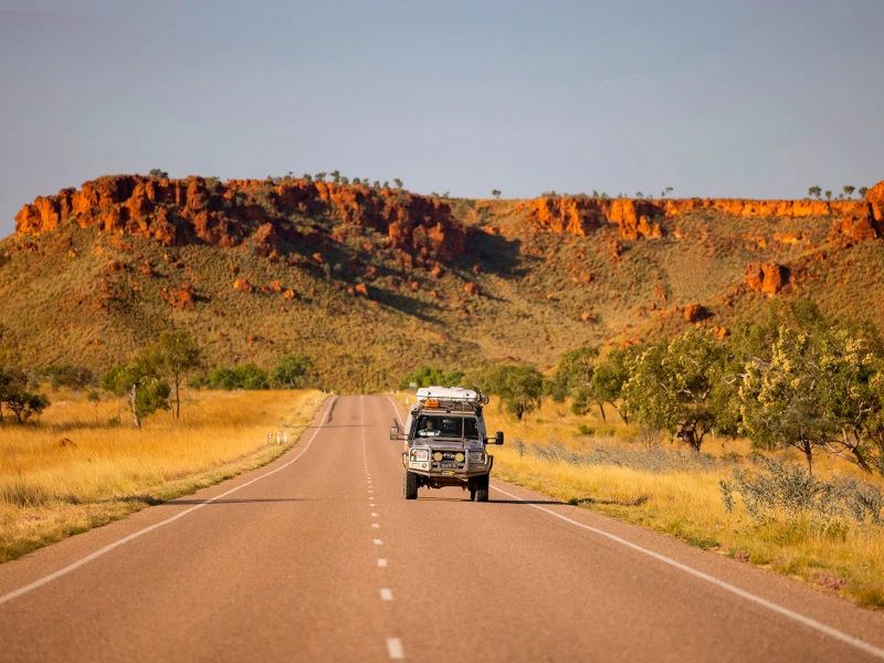 auto rijd over weg met rode rotsen op de achtergrond