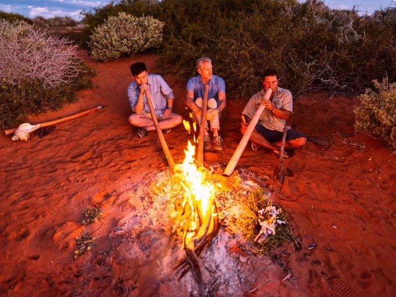mannen rondom het kampvuur met didgeridoo australie