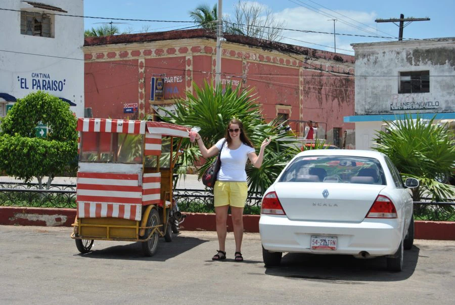 Vrouw poseert bij auto en traditioneel voertuig
