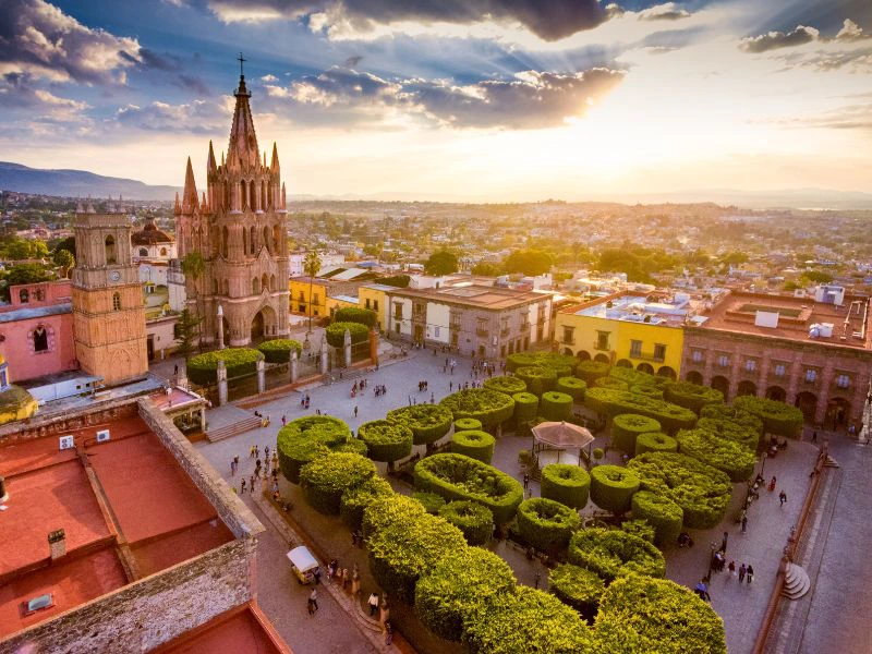 Luchtfoto van een plein in San Miguel de Allende met een kerk, een parkje in het midden en gekleurde huizen er om heen