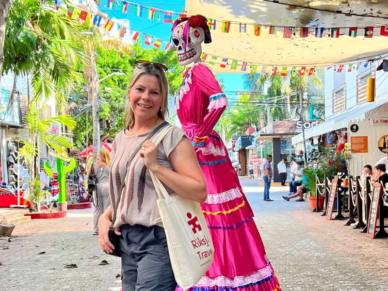 Vrouw staat op een straat bij een roze pop in Mexico