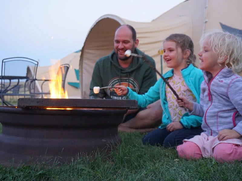 gezin met marshmallows bij het kampvuur