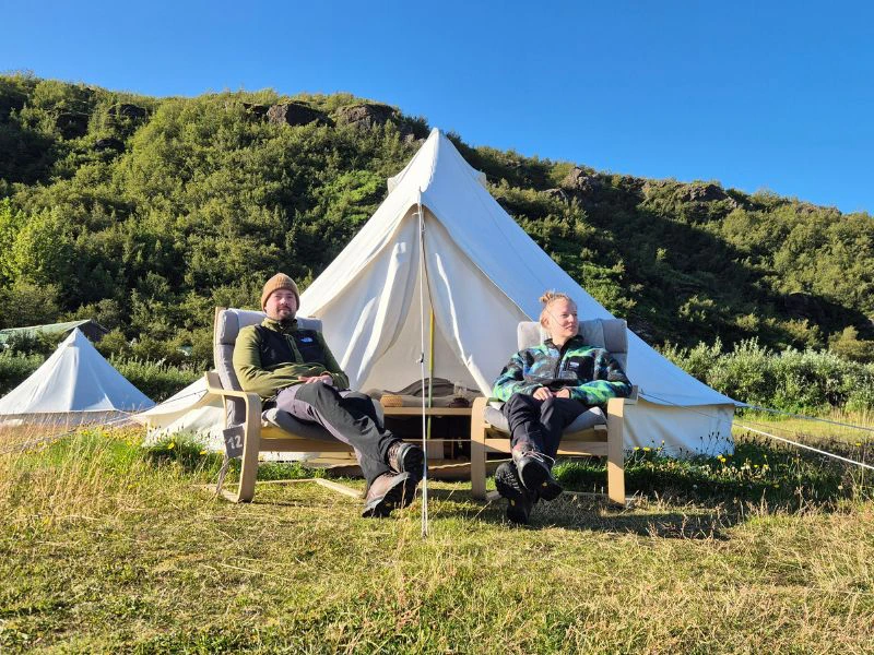 mensen zitten voor tent met natuur op de achtegrond