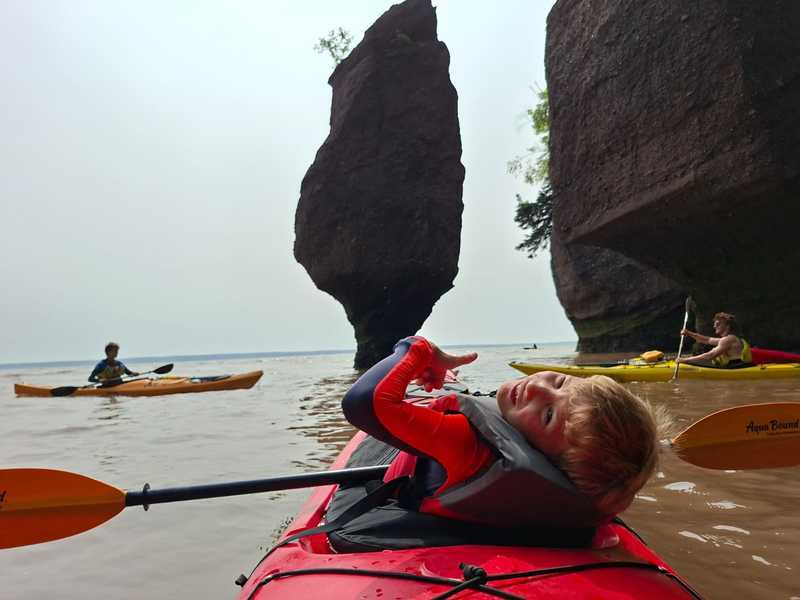 Jongen in kajak bij hopewell rocks, rotsformaties