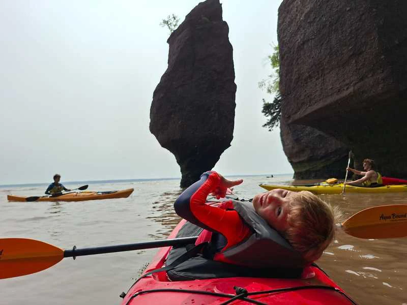 Jongen in kajak bij hopewell rocks, rotsformaties