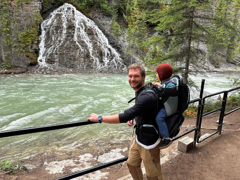 Vader staat met een kind op zijn bij een rivier in Jasper National Park.
