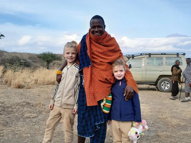 Twee zussen staan met een Masai-man op de foto.