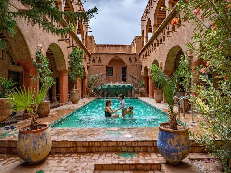 Een moeder met twee kinderen spelend in een zwembad van een Riad in Marokko.