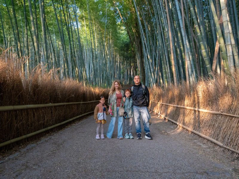 Een gezin staat samen op een rustig pad tussen hoge bamboestammen in Japan.
