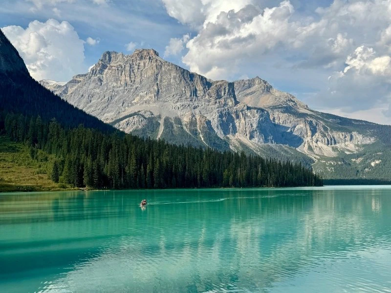 Turkoois water met eenzame roeier voor een berglandschap