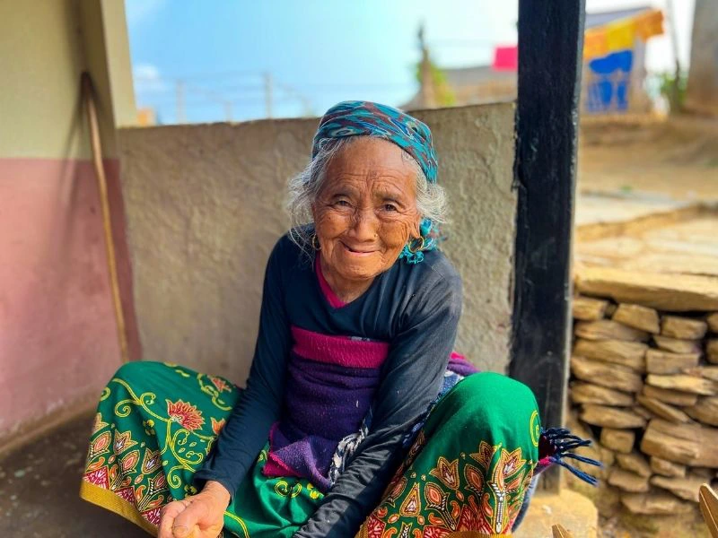 Vrouw met kleurrijke kleding zit op de grond in nepal