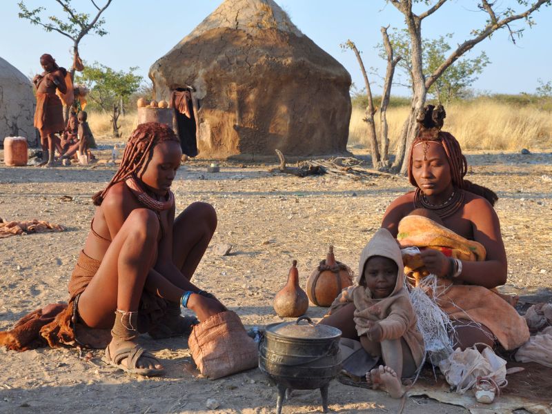 Himba vrouwen en kind zitten op de grond