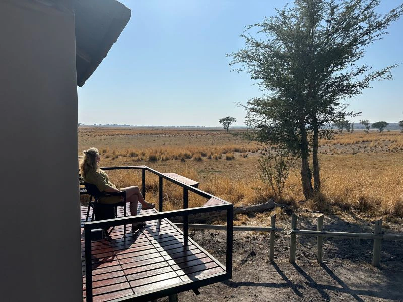 Reiziger geniet op het terras van haar lodge van het uitzicht over de Kalahari.