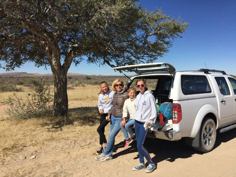 Familie leunt tegen de huurauto tijdens een pauze.