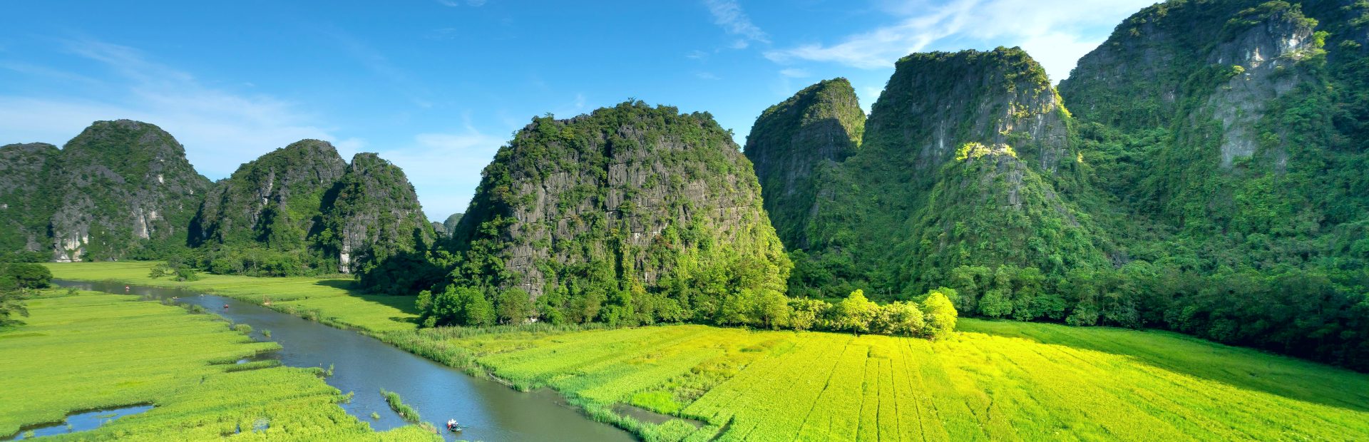 karstbergen rijzen op tussen de groene velden met een slingerende rivier op de voorgrond in Ninh Binh