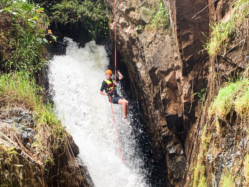 Jongen abseilt boven een waterval.