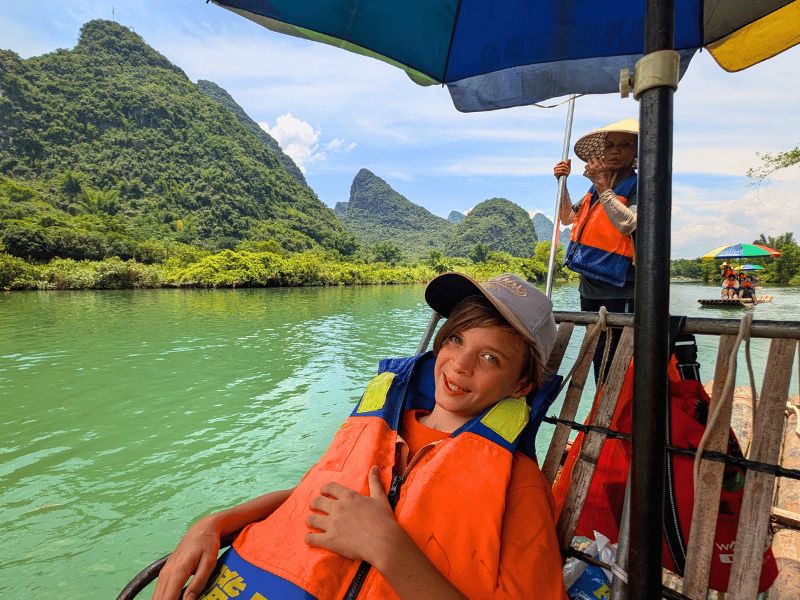 jongen op bamboevlot op rivier in Yangshuo
