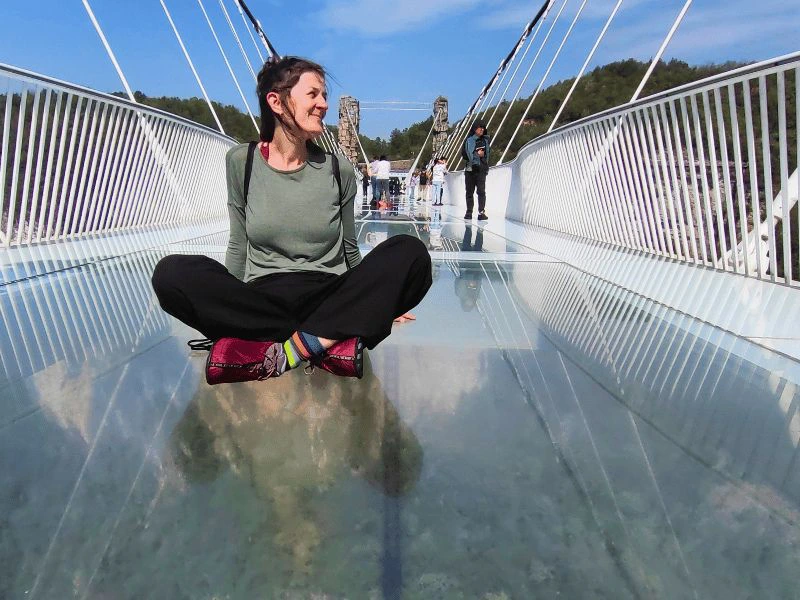 Vrouw zit op glazen brug