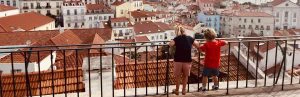 2 kinderen staan bij een hekje in Porto met uitzicht over allerlei huisjes