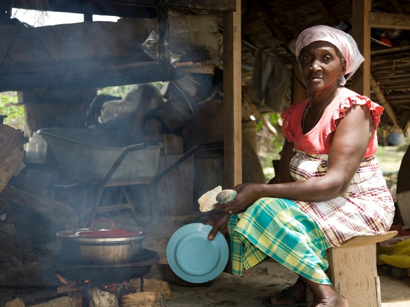 Vrouw in Suriname ia aan het koken op de grond