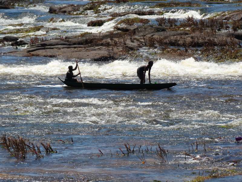 twee perosnen in een korjaal door de stroomversnelling van de Surinamerivier