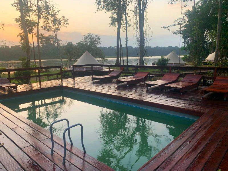 het zwembad van de glamping met ligstoellen en een tent op de achtergrond