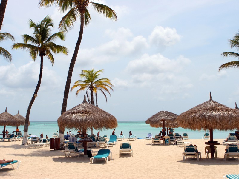 Wit strand met palmbomen en bedjes op Aruba
