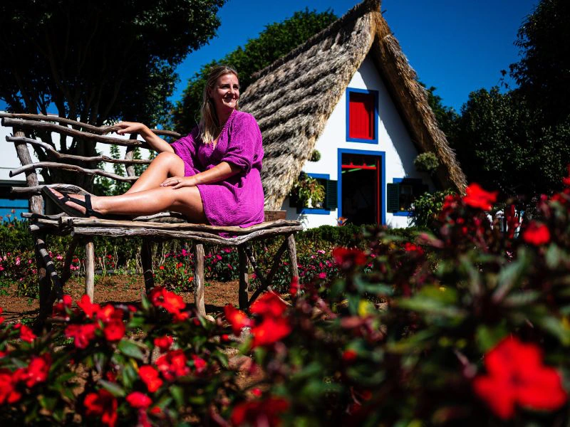 Vrouw op bankje bij huisje met rieten dak in Santana