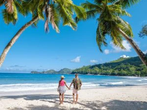 Koppel loopt over strand met palmbomen en zee