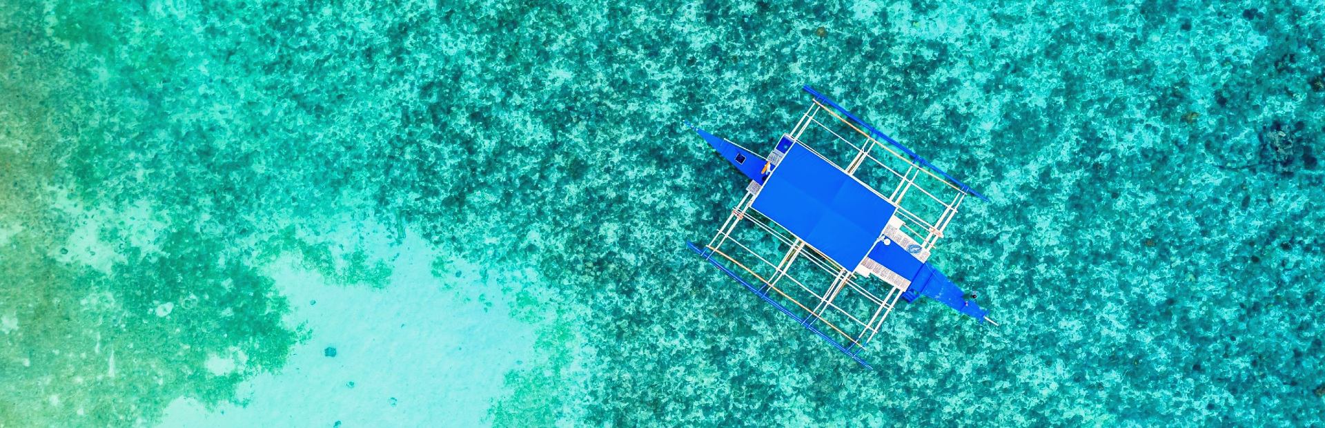 Een boot die drijft op een blauwe zee voor de kust van Moalboal