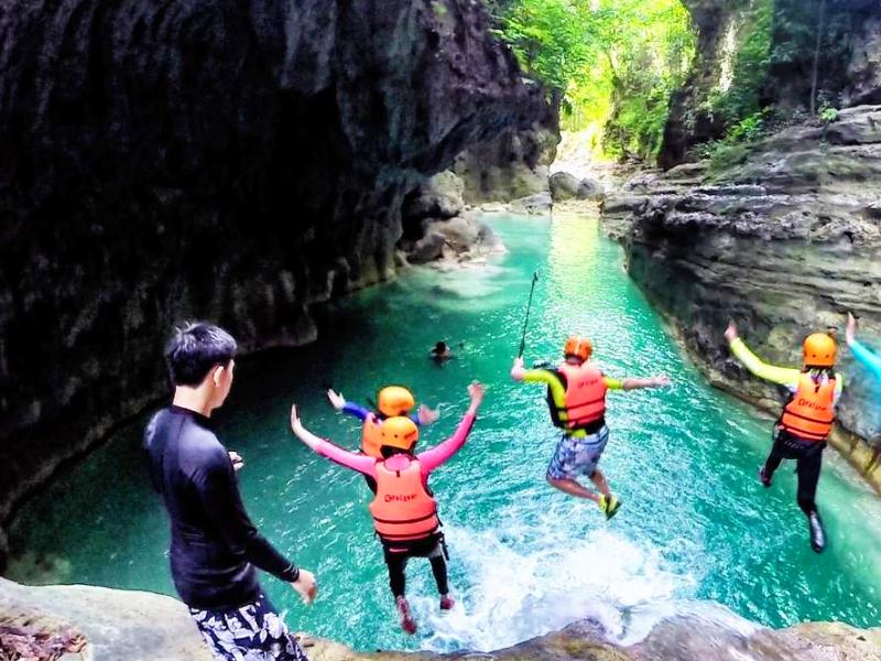 reizigers springen bij een waterval in het water, met zwemvesten, in Moalboal