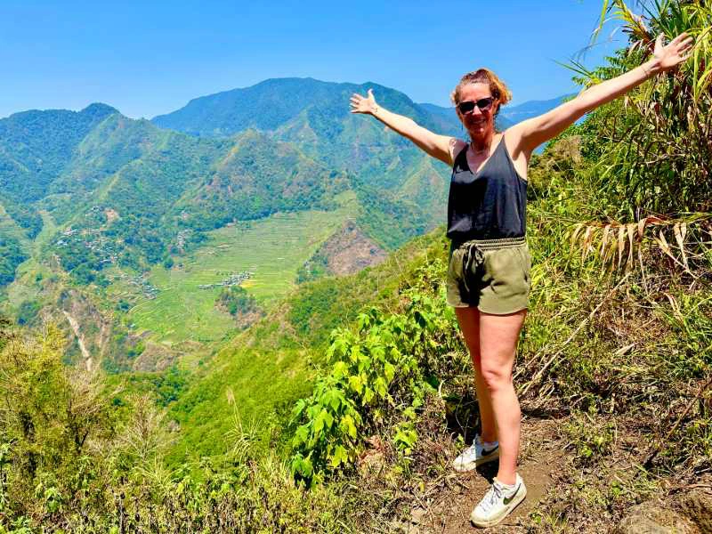 vrouw tijdens haar vakantie in de Filipijnen naast de steile rijstterrassen van Batad en Banaue, met haar armen uitgestrekt