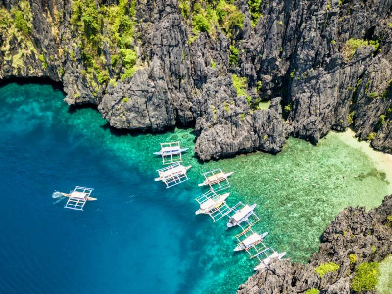 witte boten in een baai met helder groenblauw water in Palawan