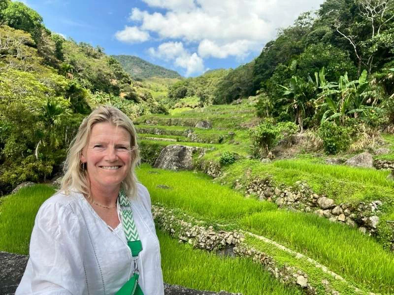 Vrouw staat voor een groen rijstterras in Banaue